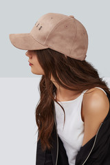 Wall Mural - Cropped side photo of a girl, wearing beige velvet baseball cap with embroidery lettering 