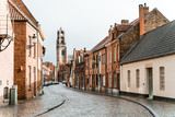 Fototapeta Uliczki - Ancient streets of the old city of Brugge in Belgium. An empty street from a lumber block extending into the distance in rainy weather.