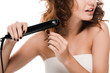 © LIGHTFIELD STUDIOS - cropped view of surprised curly woman using hair straightener isolated on white