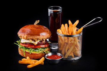 cheeseburger with fries and sauce on a black background