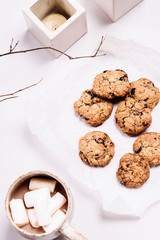 Wall Mural - Christmas cranberry and chocolate oatmeal cookies and mug of cocoa with marshmallow on white background decorated branches and candles. Selective focus