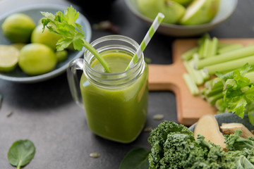 Wall Mural - healthy eating, food and vegetarian diet concept - close up of glass mug of fresh green juice or smoothie with paper straw, fruits and vegetables on slate stone background
