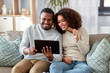© Syda Productions - family, technology, online shopping and people concept - happy african american couple couple with tablet pc computer and credit card at home