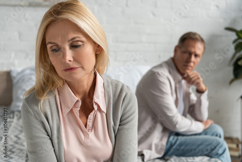 Cuadros en Lienzo Selective focus of worried woman with husband sitting on bed