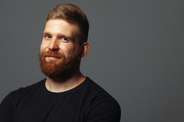 Fabulous at any age. Close up portrait of charismatic muscular 30-year-old man standing over dark gray background. Perfect haircut. Rocker, biker, hipster style. Copy-space. Studio shot