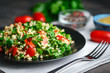 Traditional oriental salad Tabbouleh with bulgur and parsley on a dark background.