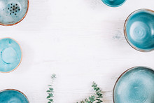White Rustic Kitchen Background. Blue Stoneware, Green Floral Decor On Wooden Table.