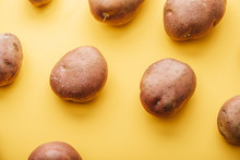 Pattern Of Raw Whole Fresh Potatoes On Yellow Background