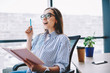 © BullRun - Emotional woman in casual wear ans spectacles satisfied with get brilliant ideas for startup holding notebook for noting, creative female writer happy about recalling information for article