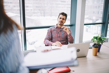 Wall Mural - puzzled male employee listening information during presentation in company office from female collea