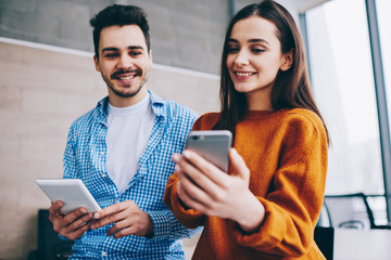 Wall Mural - cheerful man and woman reading funny news in social network via smartphone device using 4g wireless 