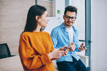 Wall Mural - smiling successful coworkers watching video online on smartphone spending free time from work togeth