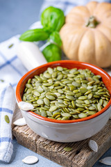 Wall Mural - Raw pumpkin seeds in a ceramic bowl.