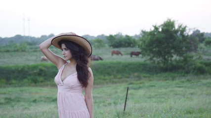 Beautiful woman standing staring at the camera with her hands on her hat