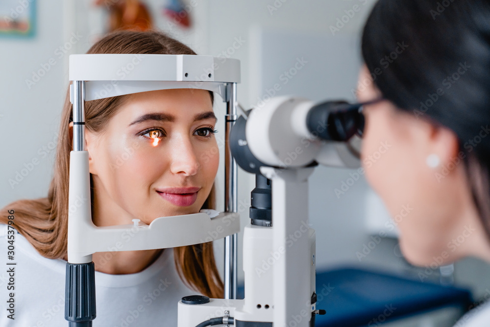Eye doctor with female patient during an examination in modern clinic - obrazy, fototapety, plakaty 