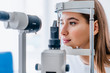 Leinwandbild Motiv Beautiful young girl checking the eye vision in modern ophthalmology clinic