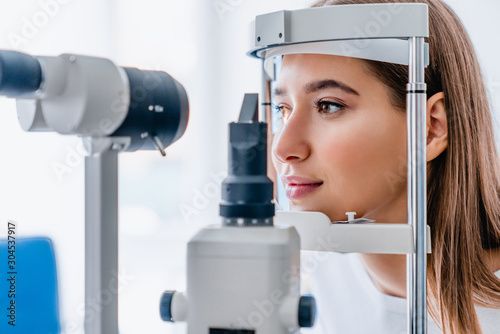 Fotomural Beautiful young girl checking the eye vision in modern ophthalmology clinic
