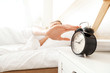 © Pixel-Shot - Morning of young woman turning off alarm clock while sleeping in bed