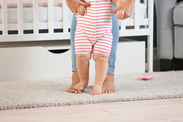 Wall Mural - Mother teaching her little baby to walk at home