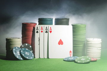 Wall Mural - Four aces cards and poker chips in the smoke on the green table background.
