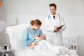 Wall Mural - Young woman with newborn baby and gynecologist in maternity hospital