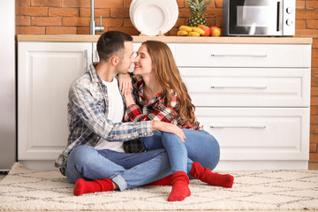 Sticker - Happy young couple sitting on floor in kitchen