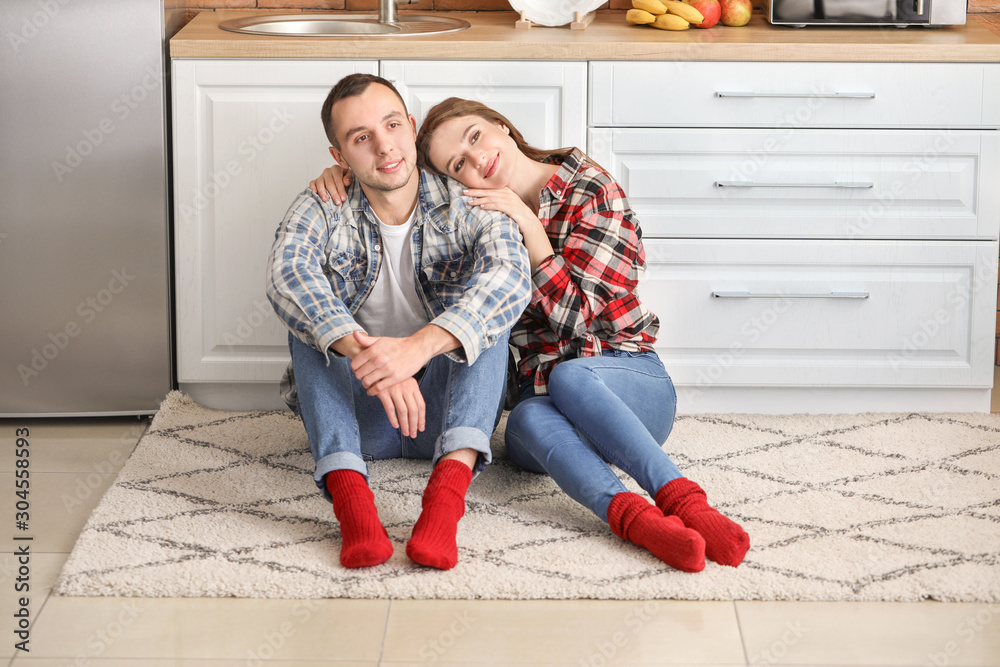 Happy young couple sitting on floor in kitchen