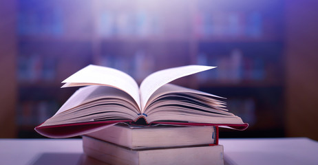 Poster - Stack of books in the library and blur bookshelf background