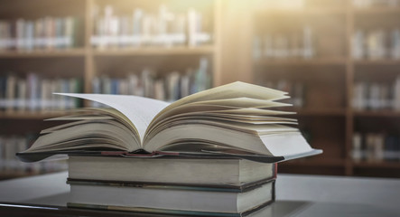 Poster - Stack of books in the library and blur bookshelf background