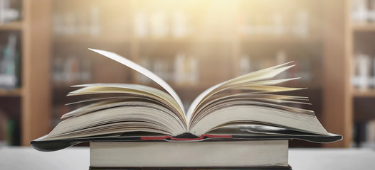 Poster - Stack of books in the library and blur bookshelf background