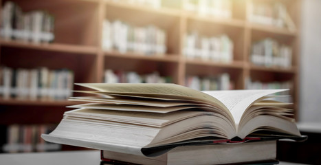 Poster - Stack of books in the library and blur bookshelf background