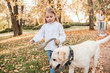 © zadorozhna - Little beautiful girl and parents walking with dog labrador in the park.