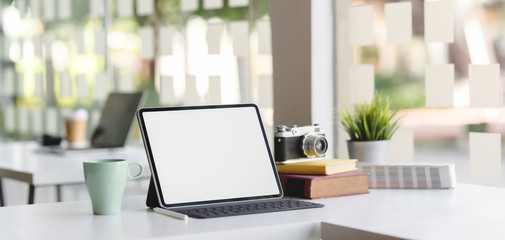 Modern office room with blank screen tablet, camera and office supplies