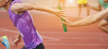 Professional Athlete Passing A Baton To The Partner Against Race On Racetrack.selective Focus.