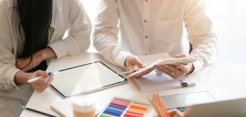 Close-up view of two young professional graphic designer planing their project while using blank screen digital tablet in modern office