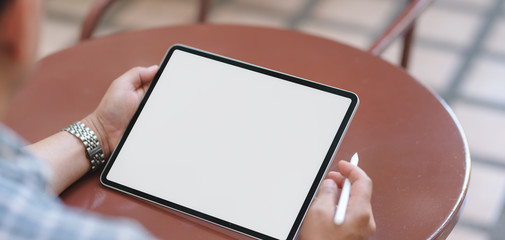 Close-up view of young businessman working on his project with blank screen tablet while sitting