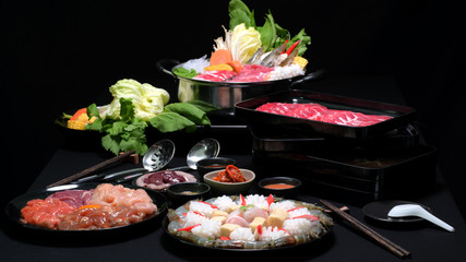 Set of shabu shabu in hot pot, fresh sliced meat, sea food and vegetables with black background