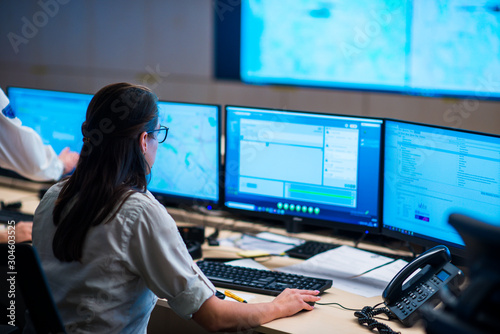 Female security guards working in surveillance room, monitoring cctv and discussing.