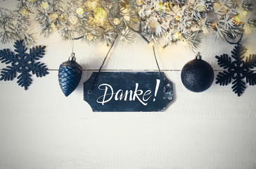 Wall Mural - Black Chirstmas Plate With German Text Danke Means Thank You. Fir Branch With Fairy Lights On Wooden Background