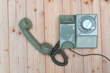 Retro rotary telephone with cable on wood table, wooden background, top view with copy space, vintage communication concept.