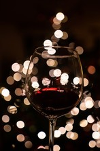Vertical Closeup Shot Of A Glass Of Wine With Bokeh Lights In The Dark Background
