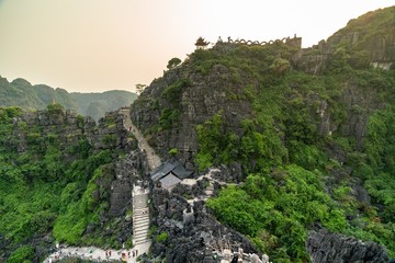 Poster - High angle shot of high rocky mountains with green trees and curvy pathways