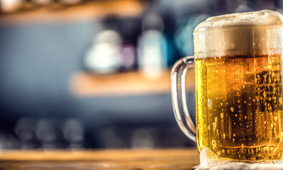 Wall Mural - Mug of cold beer on bar counter in pub or restaurant