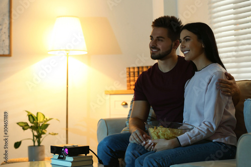 Cuadros en Lienzo Young couple watching movie using video projector at home