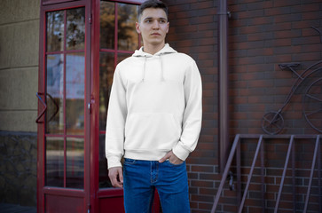 Poster - Presentation of a white hoodie on a young guy on the street, front view.