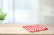 Red checkered folded picnic cloth on wooden table empty space background.