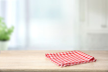 Red Checkered Folded Picnic Cloth On Wooden Table Empty Space Background.