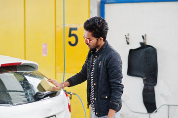 South asian man or indian male washing his white transportation on car wash.