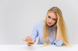 © Вячеслав Чичаев - Concept woman with alcohol problems sits at a table with whiskey in a glass. Portrait of a beautiful blonde girl with excellent makeup with long smooth hair on a white background in a blue shirt.