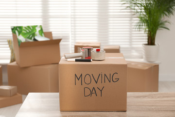 Wall Mural - Cardboard box with words MOVING DAY and packaging items on wooden table